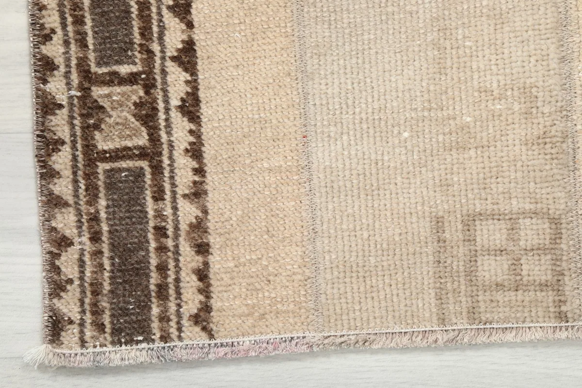 Corner detail of the rug, showing the short, natural fringe and the start of the geometric border.