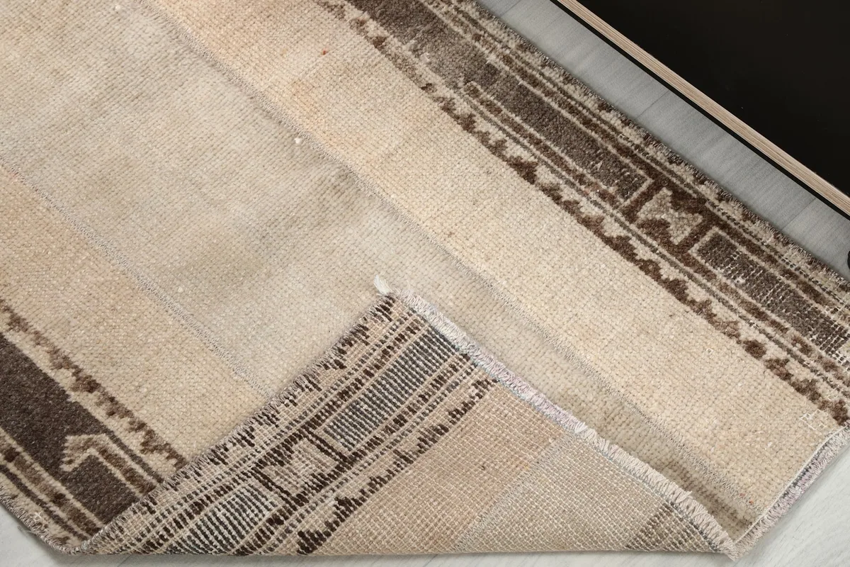 Corner of the rug folded back, revealing the cotton foundation and the reverse side of the knotting.