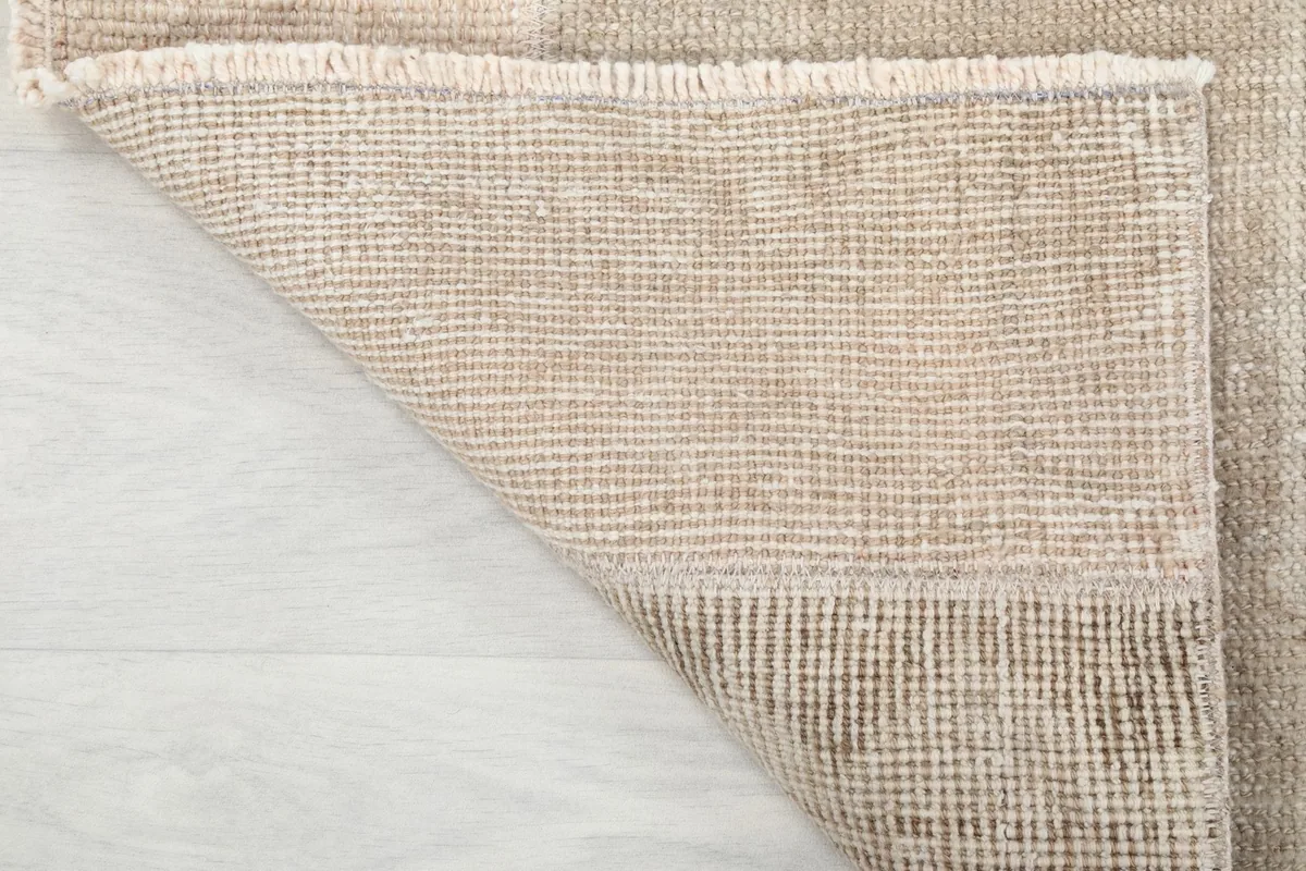 Close-up of the fringe and a folded corner, showing the wool pile and cotton foundation of the rug