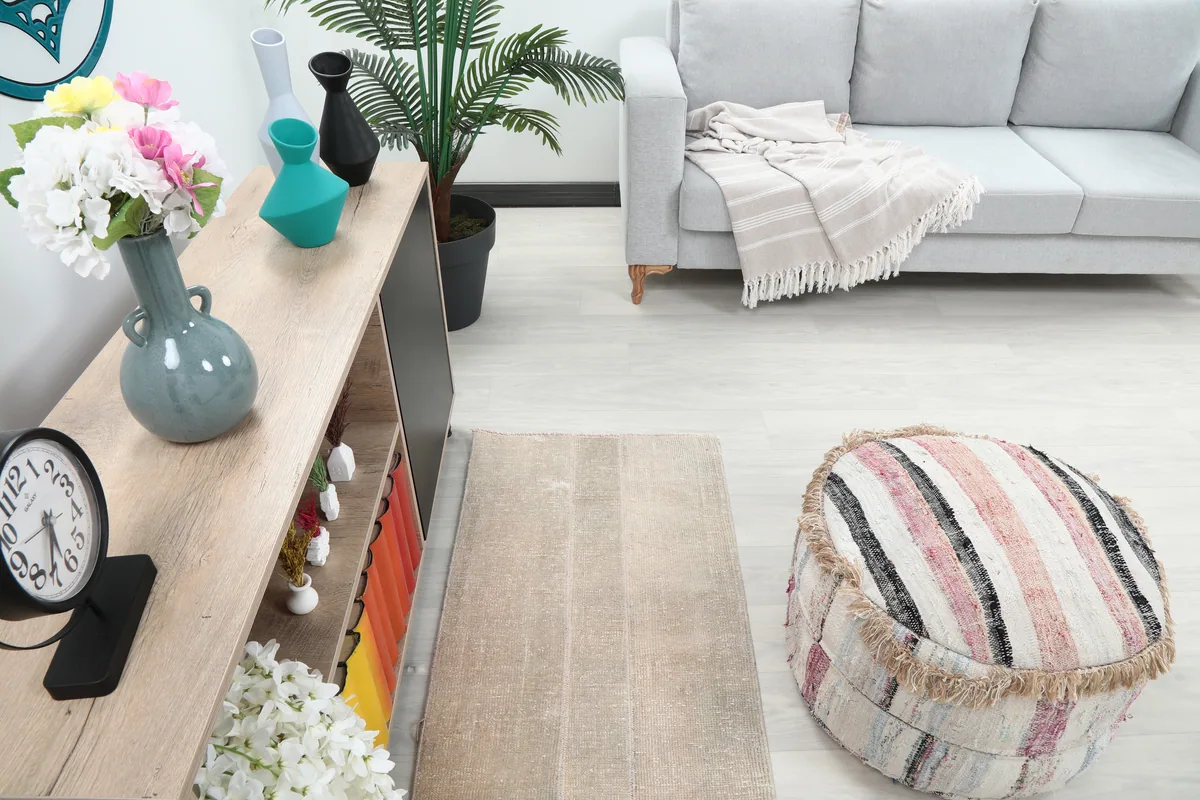 Overhead view of the Faded Beige Minimalist Anatolian Rug in a room with a sofa and pouf.