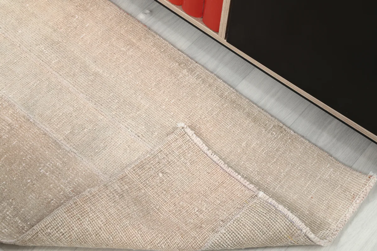 Faded Beige Minimalist Anatolian Rug folded back to reveal the cotton foundation and hand-knotted construction.