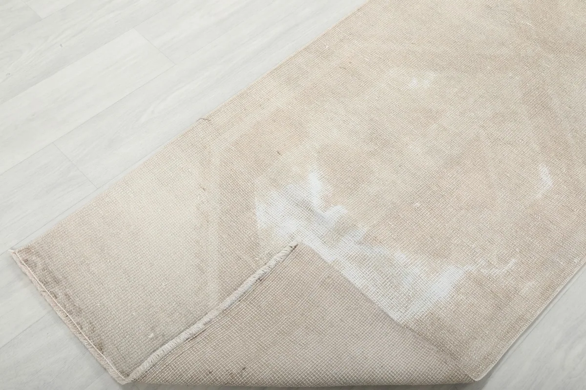 Corner of the rug folded back, revealing the cotton foundation and reverse side