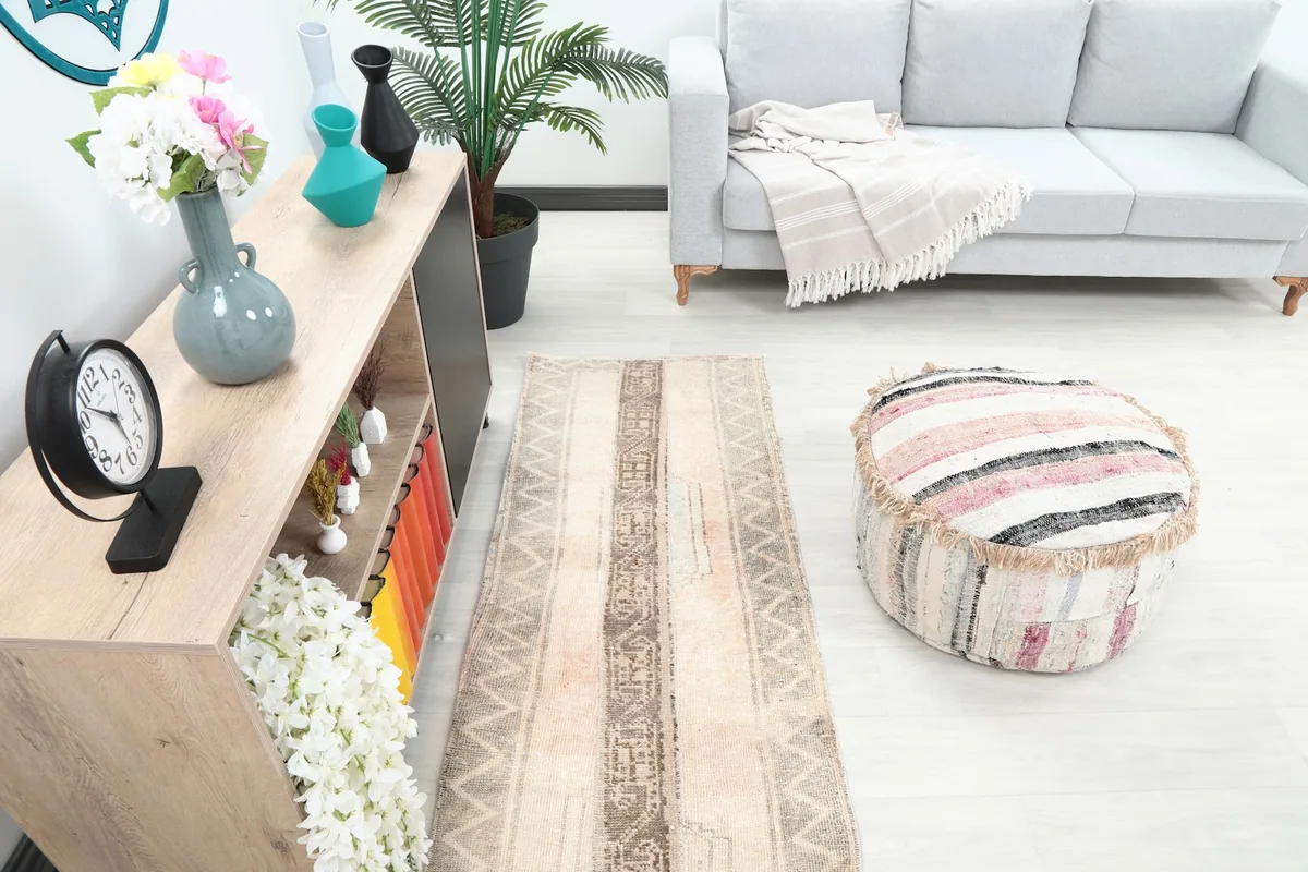 Runner rug placed in a room showing a gray couch and decorative ottoman