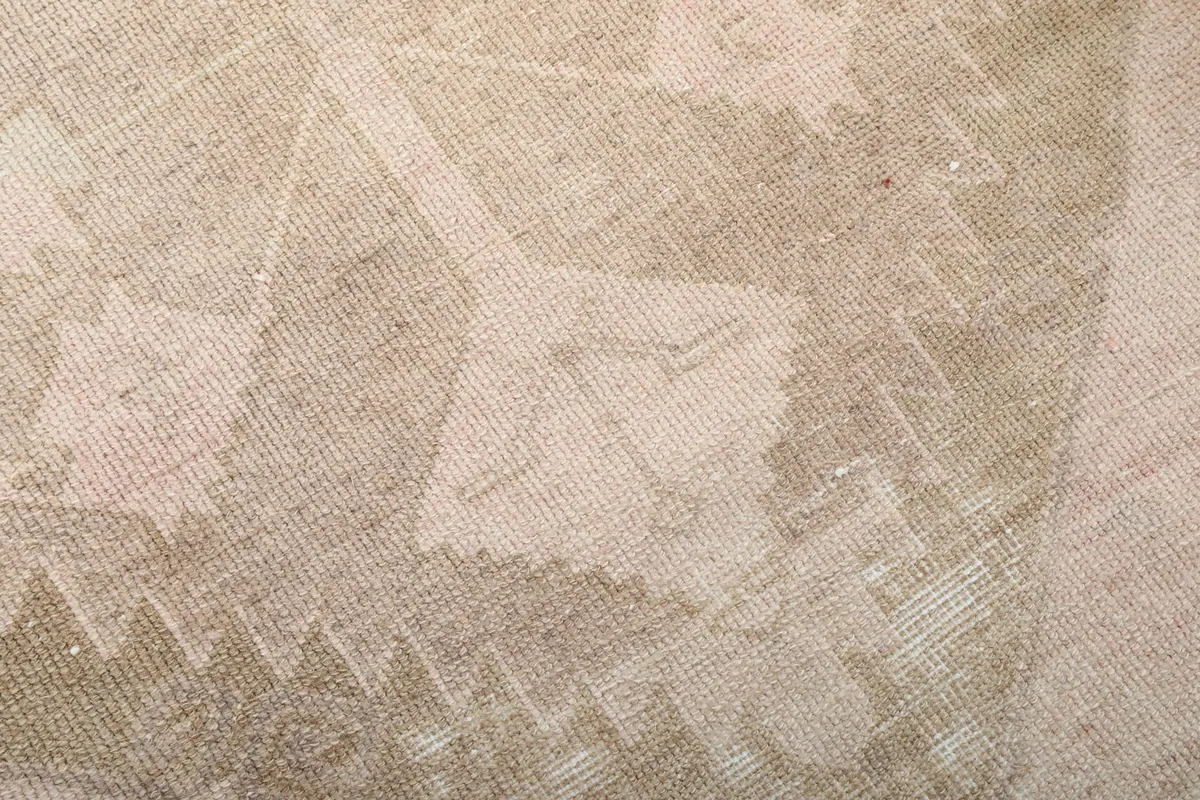 Close-up of the low wool pile texture and faded beige patterns of the hand-knotted runner