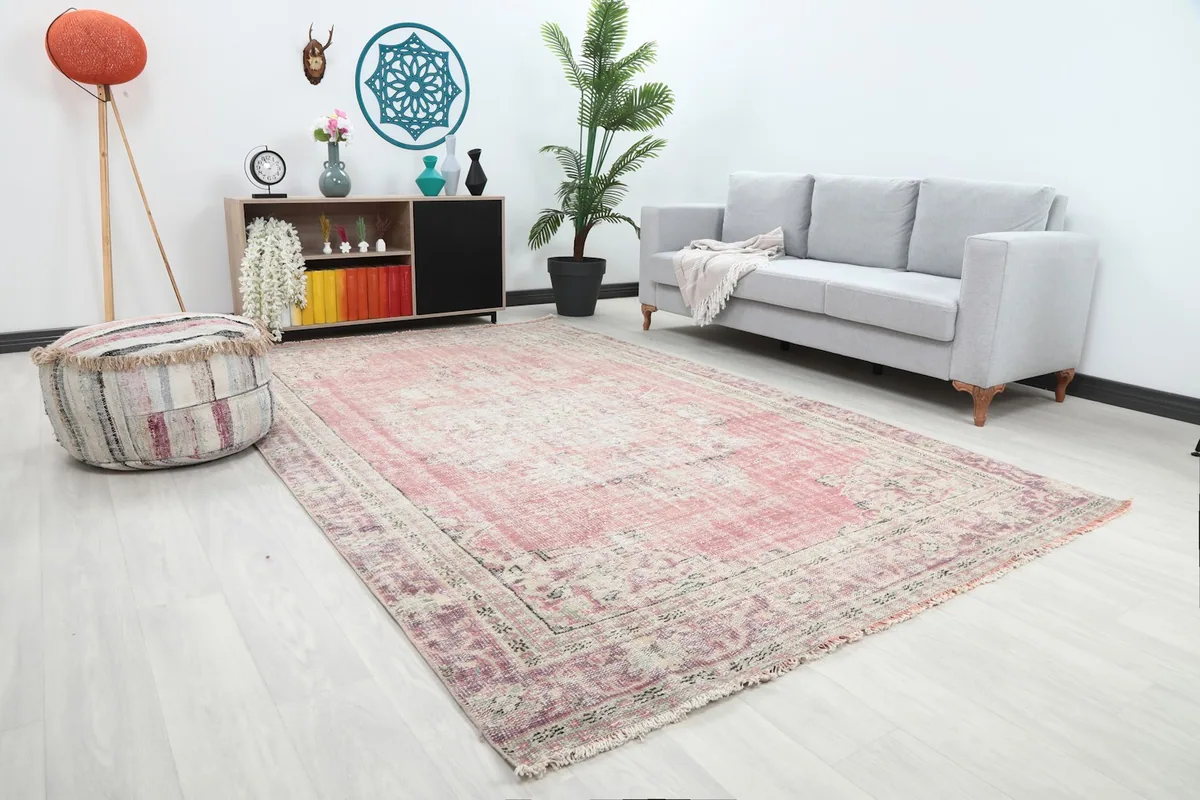 Angle view of the rose Anatolian rug in a living room, showing its placement relative to furniture