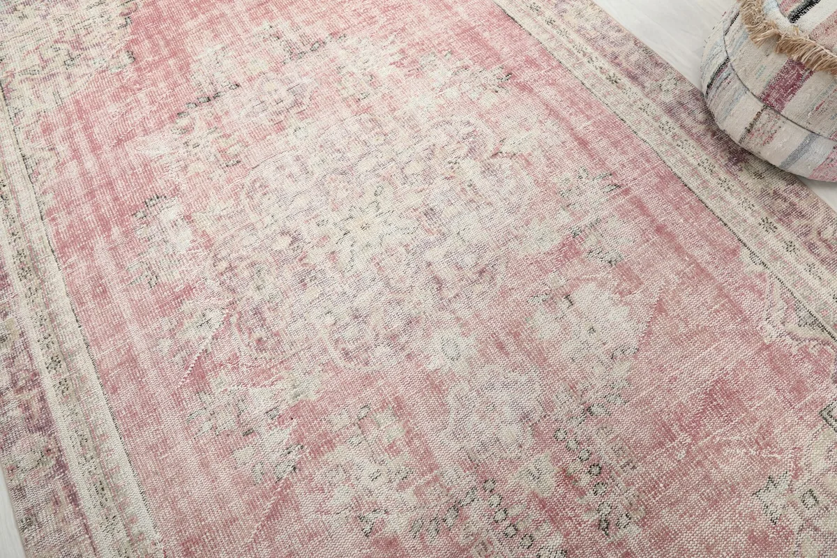Close-up detail of the faded rose color and subtle geometric patterns in the rug's field