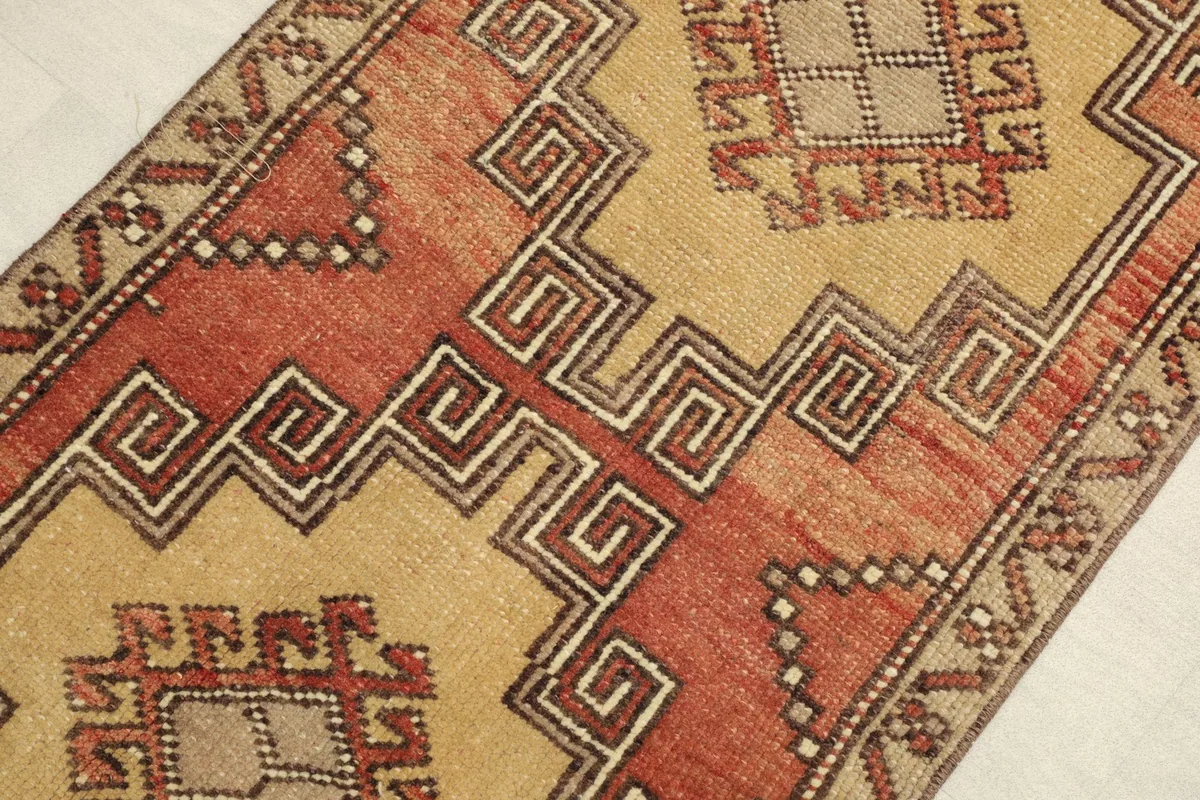 Close-up view of the rug's geometric patterns and color variations between rust and beige.