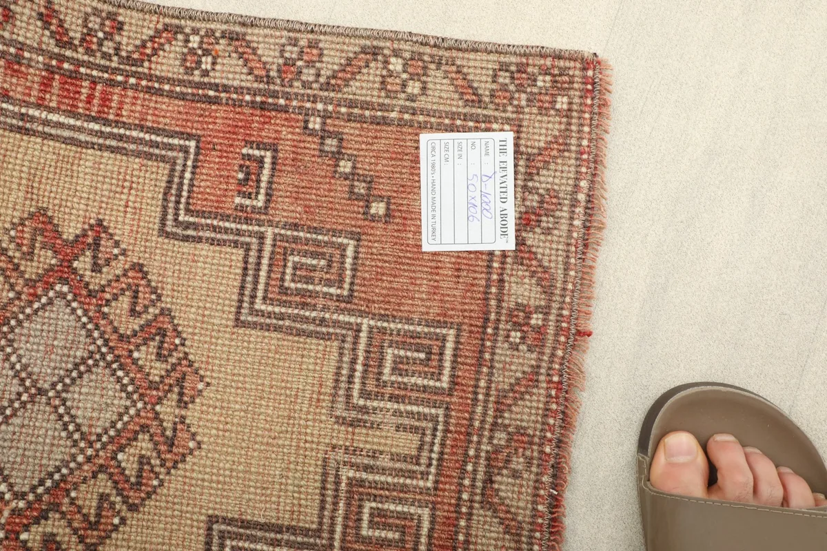 Back of the rug showing the hand-knotted construction and a size reference with a foot.