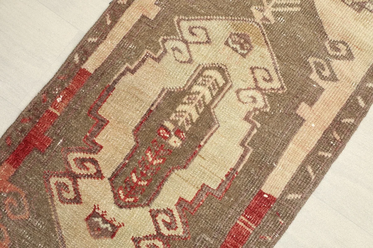 Close-up detail of the central beige field and brown geometric motifs of the rug.