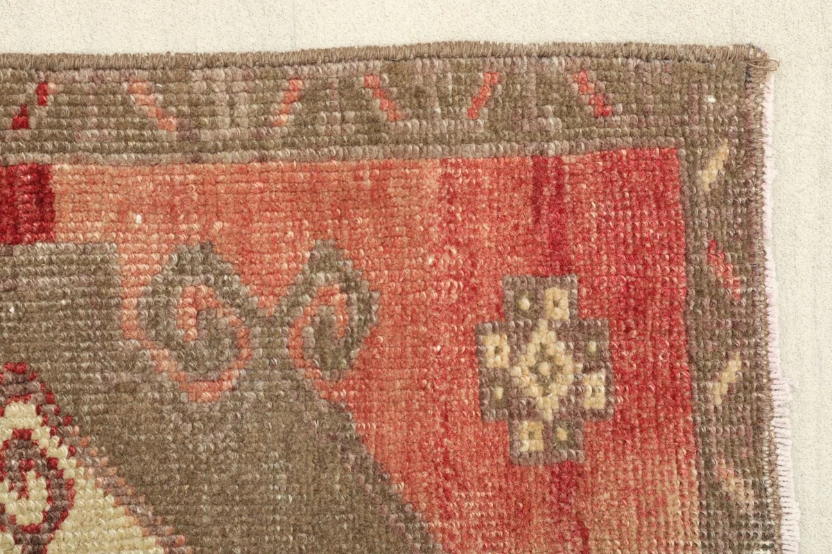 Close-up of the rug's corner, showing the brown border and rust field with minor wear.