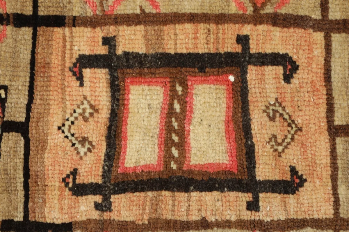 Detailed view of the intricate central motif and surrounding tribal patterns on the rug.