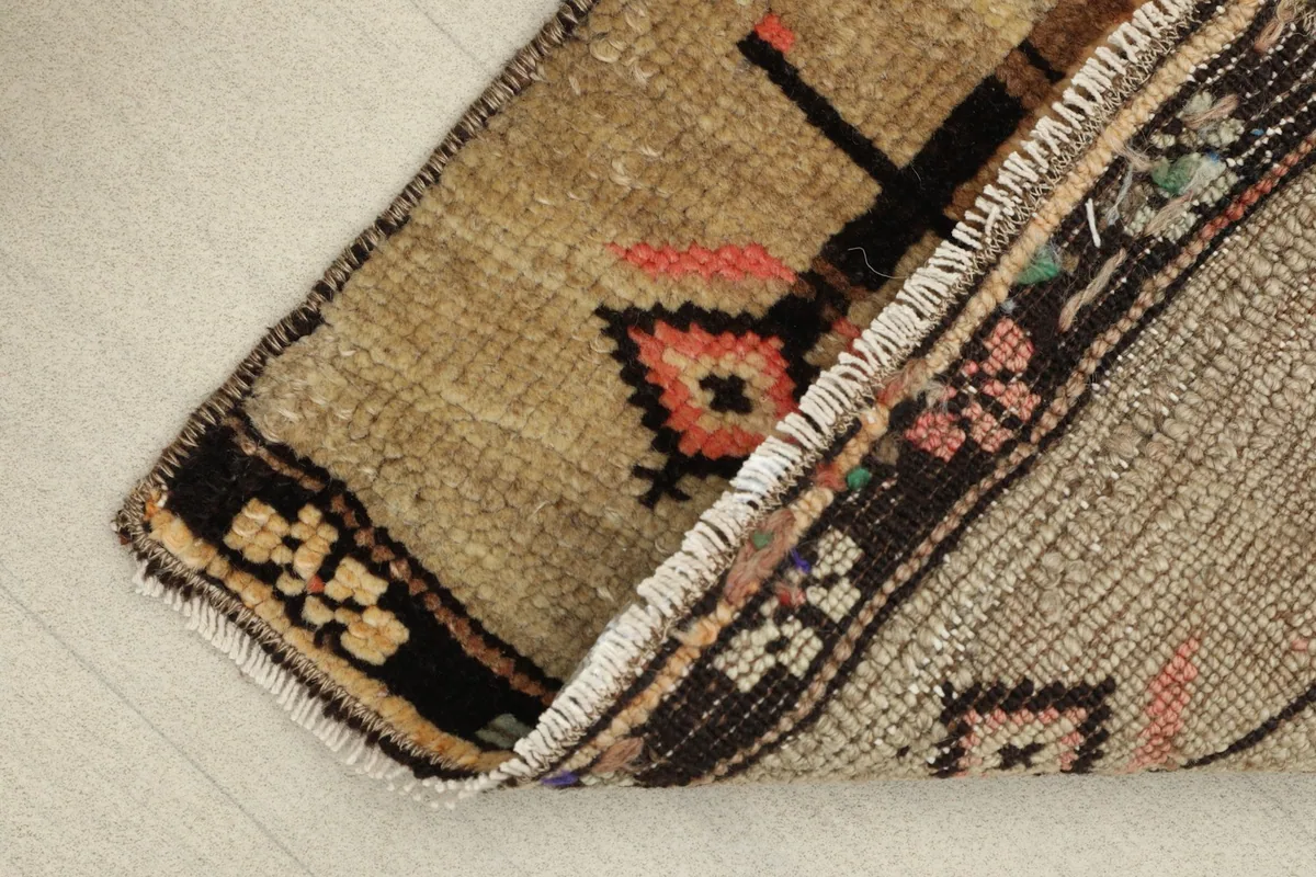 View of the rug's low wool pile and the reverse side, showing its construction and fringes.