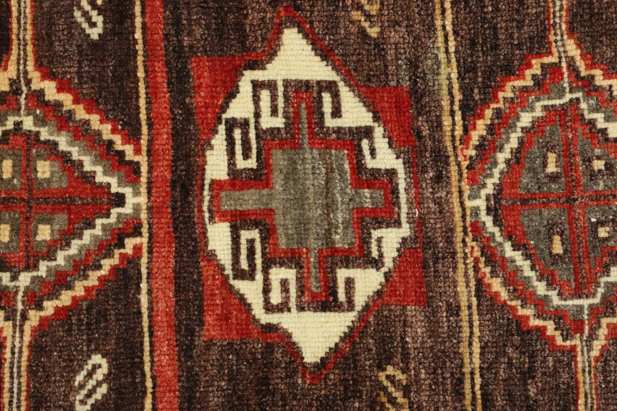 Close-up detail of the central geometric motif with red, beige, brown, and gray tones.
