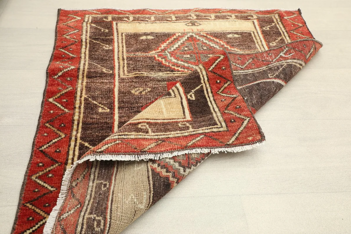 Rug partially folded, revealing the cotton foundation and the reverse side of the vintage doormat.