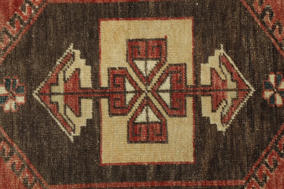 Close-up detail of the central geometric motif in brown, rust, and ivory colors
