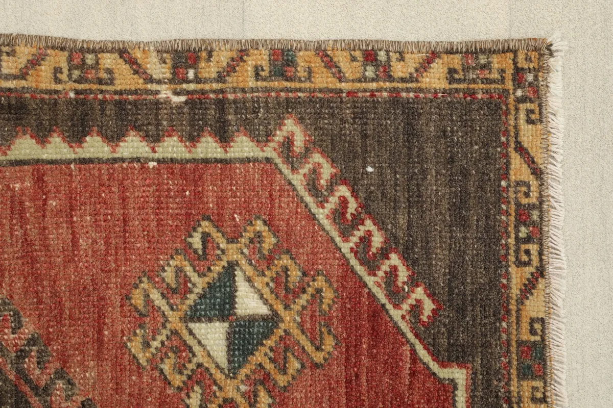 Close-up of a side motif within the rust field, featuring green and blue accents