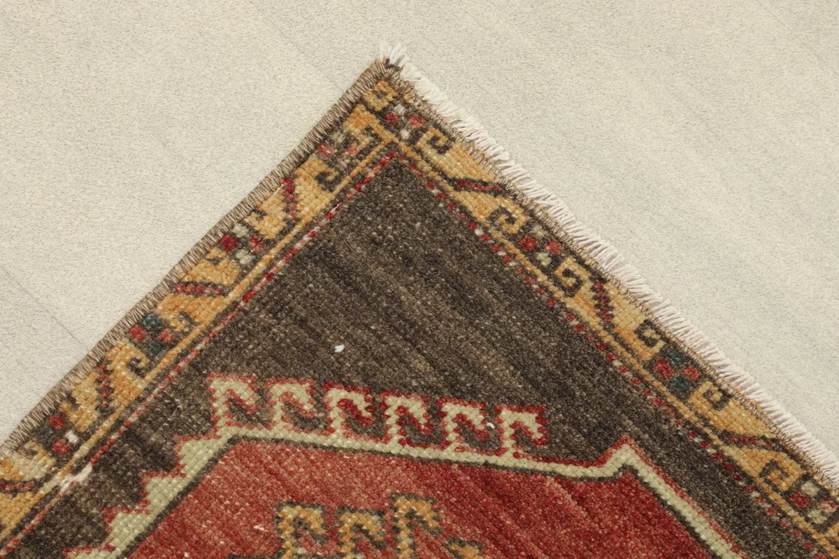 Corner detail showing the brown and beige geometric border pattern and a glimpse of the fringe