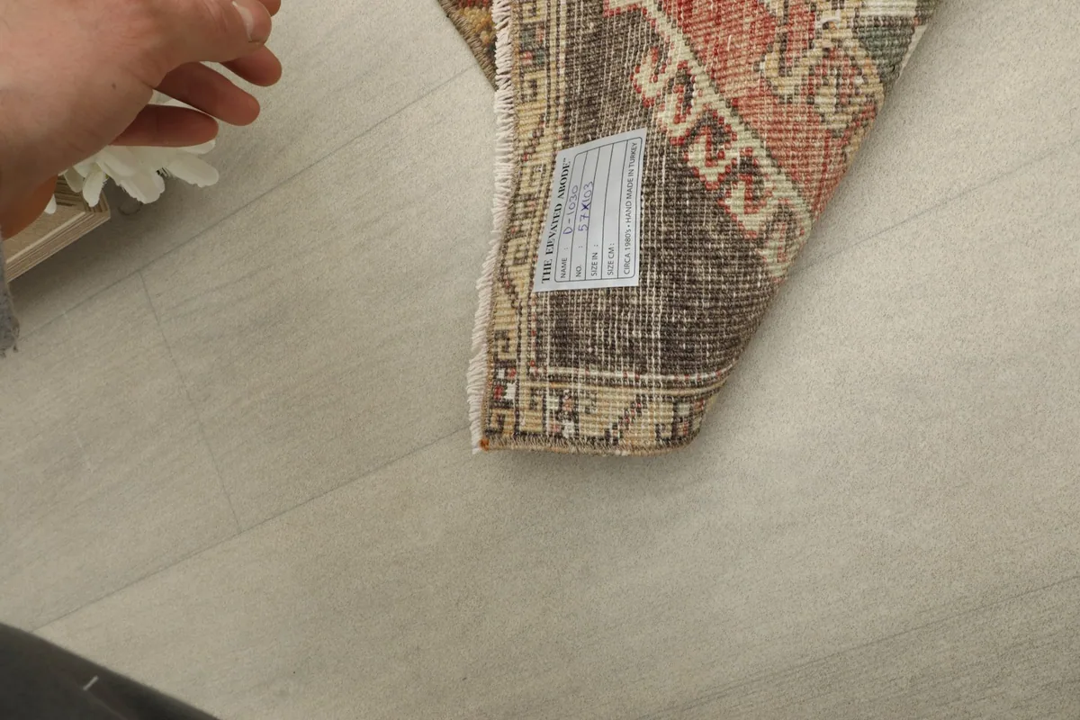 Hand touching the low pile of the vintage wool rug, displaying its texture and condition