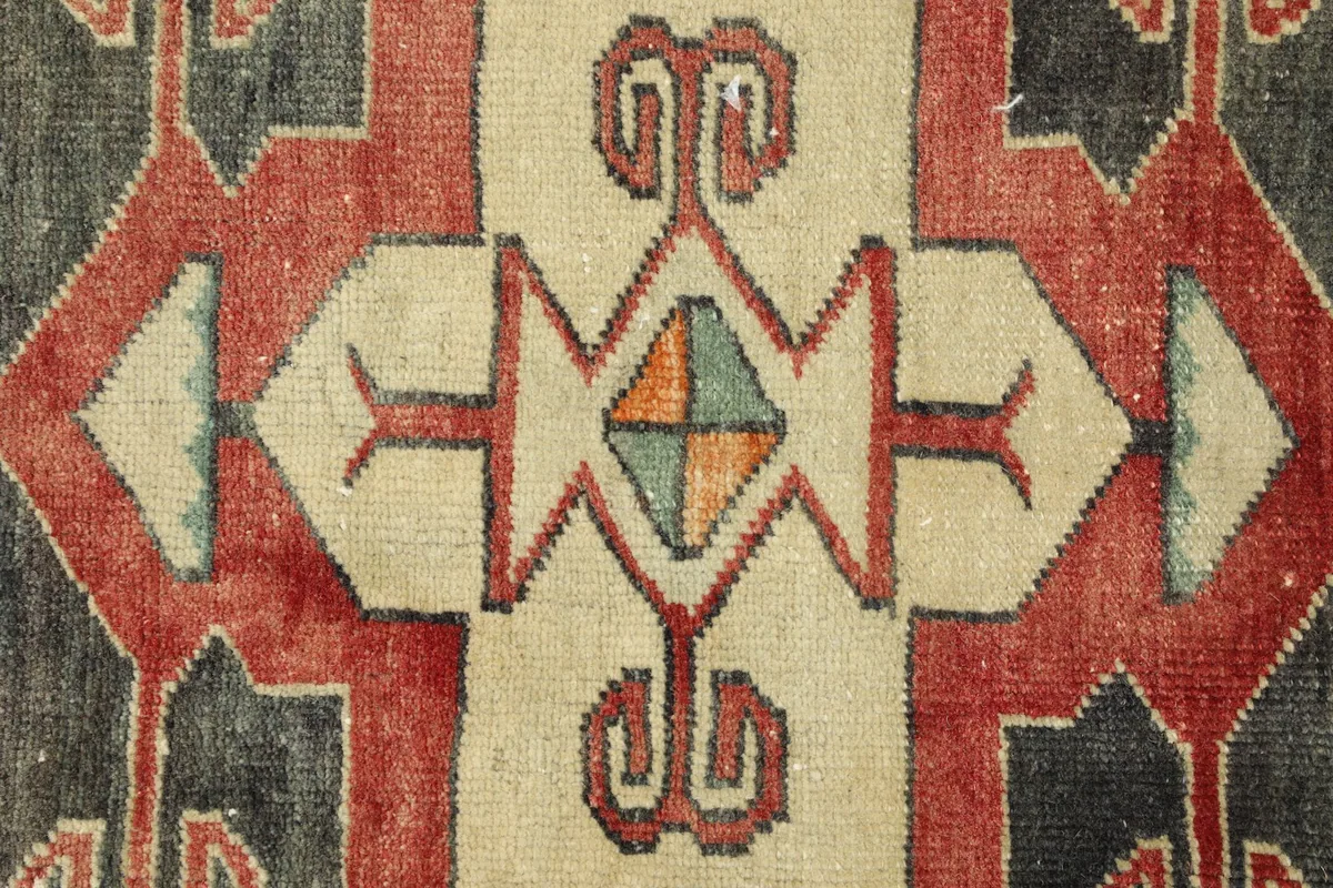 Close-up detail of the central ivory geometric motif with accents of red, green, and orange.
