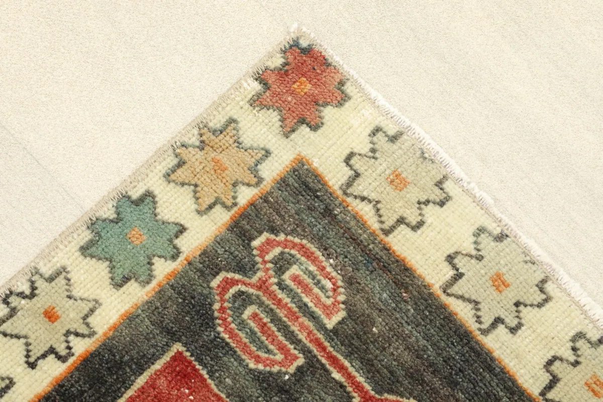 Corner detail showing the ivory border with multicolor star-like motifs and the charcoal field.