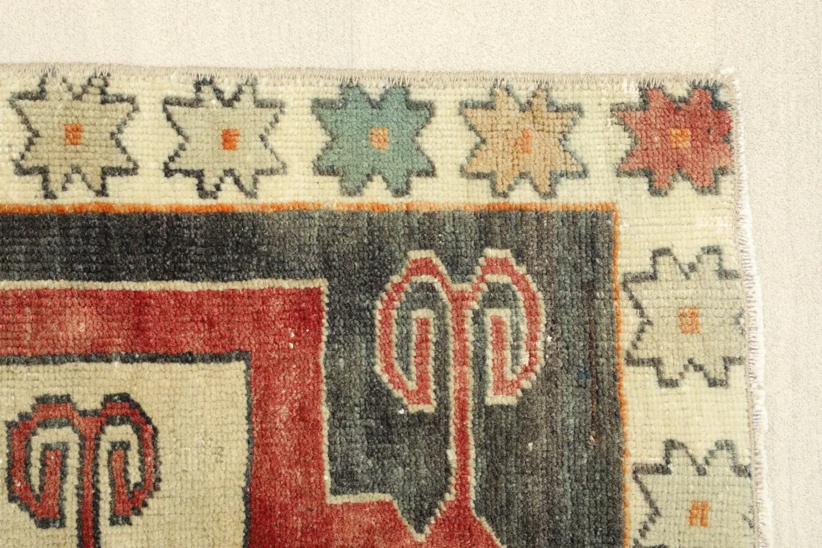 Side border detail of the vintage wool rug, displaying the patterned ivory edge and charcoal field.