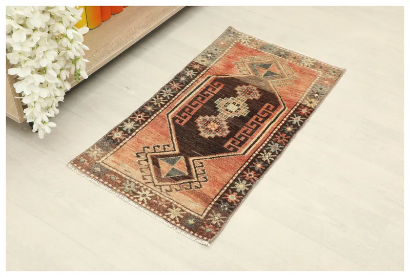 Full top view of the 1'6" x 2'9" rust and brown vintage Anatolian rug on a white floor