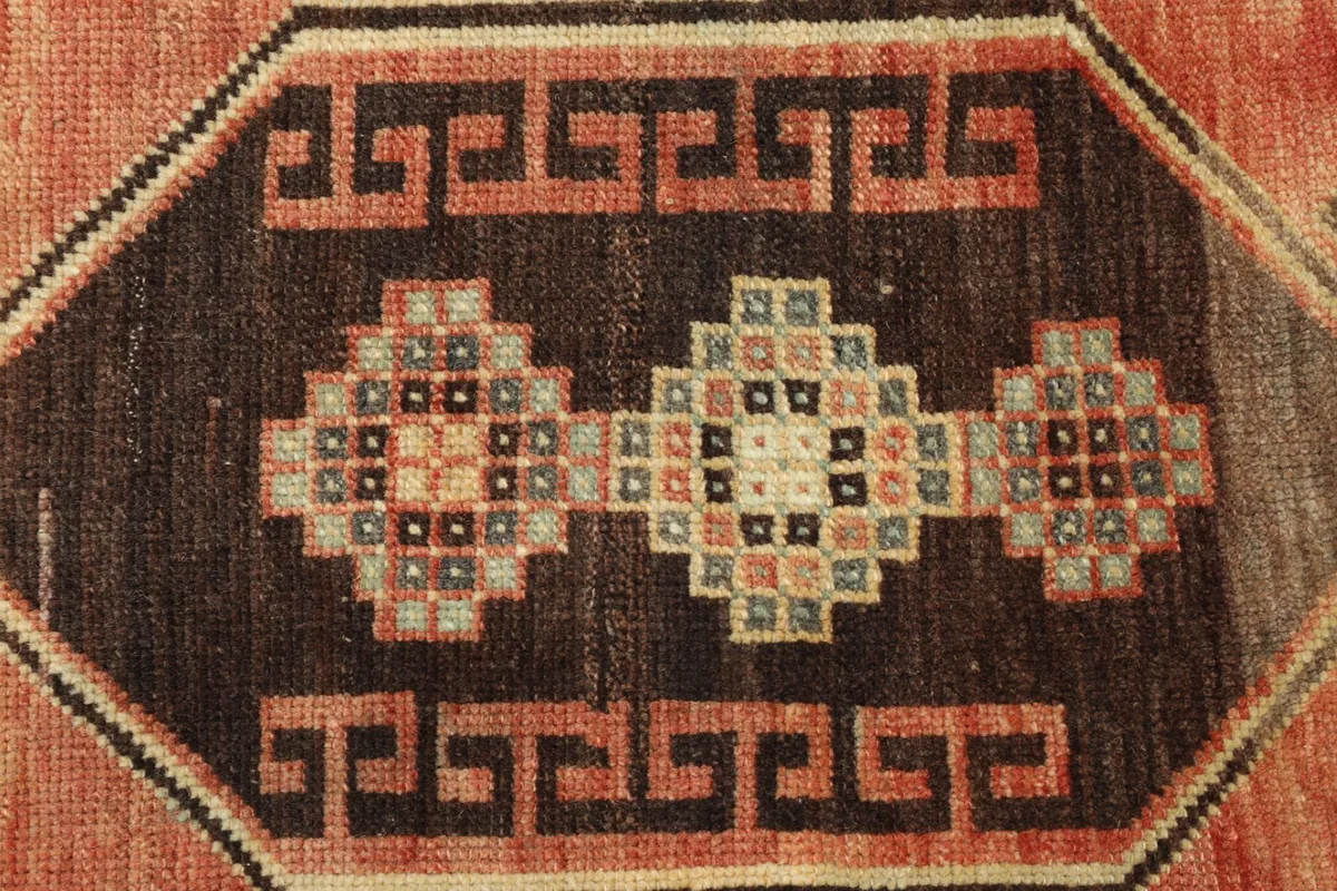 Tight detail shot of the brown geometric medallion with accent colors like blue and pink