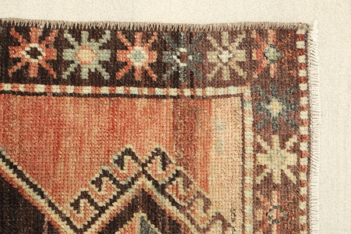 Side border detail of the vintage rug, showing the intricate patterns and low pile texture
