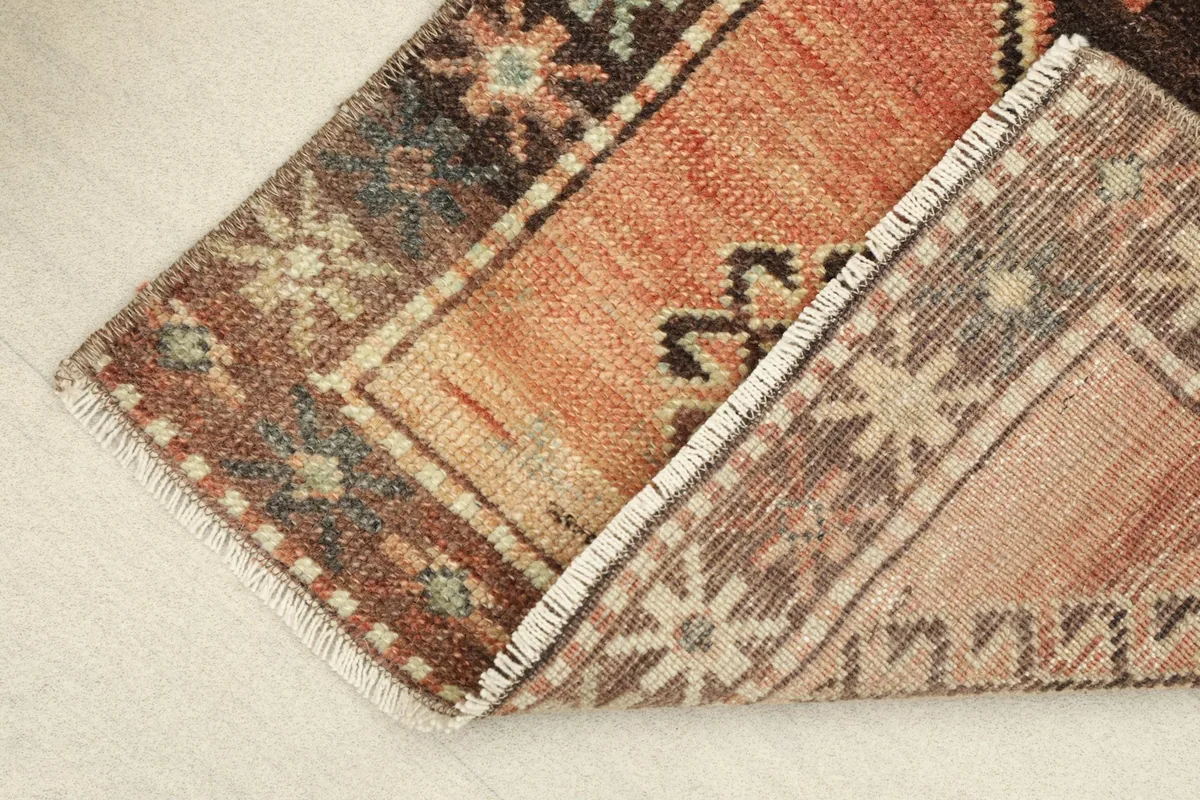 Rug corner folded back to reveal the back of the hand-knotted cotton foundation and wool pile