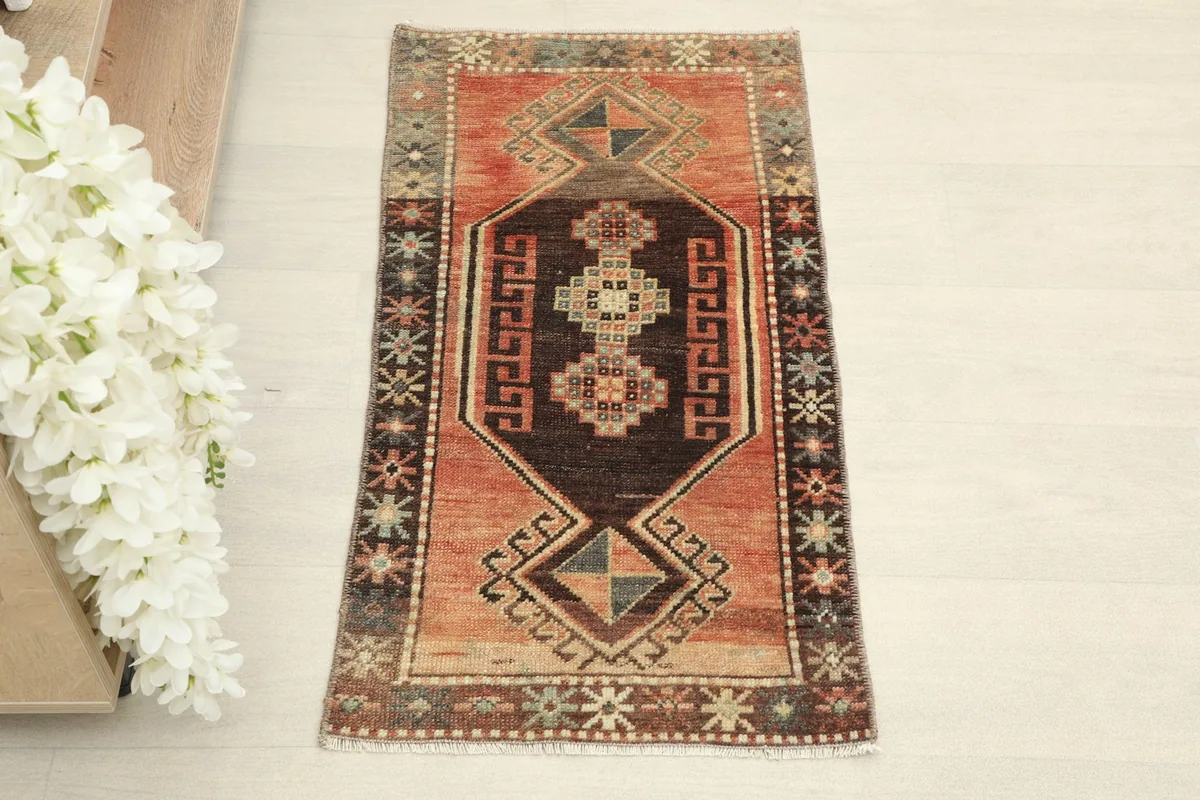 Overhead view of the small hand-knotted rug, highlighting its rust field and brown geometric patterns