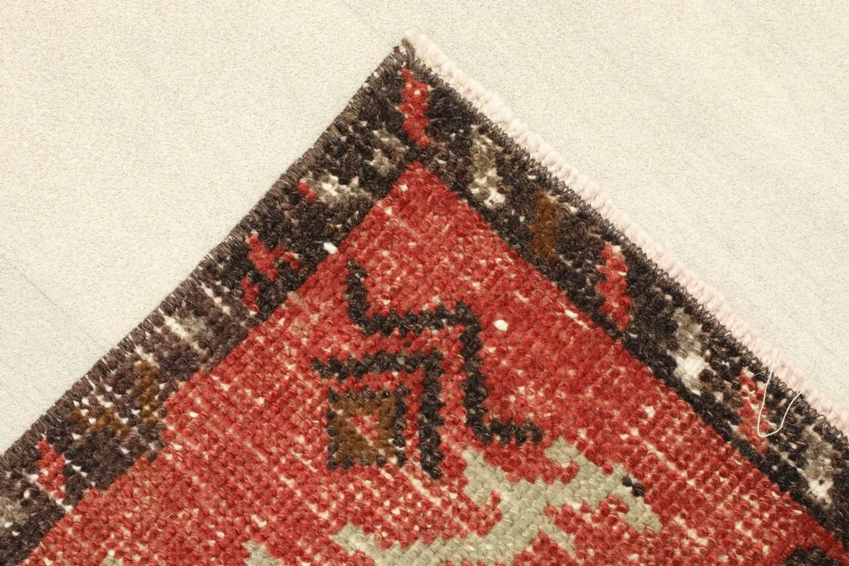 Corner detail of the rug, showing the rust border with brown and beige accents.