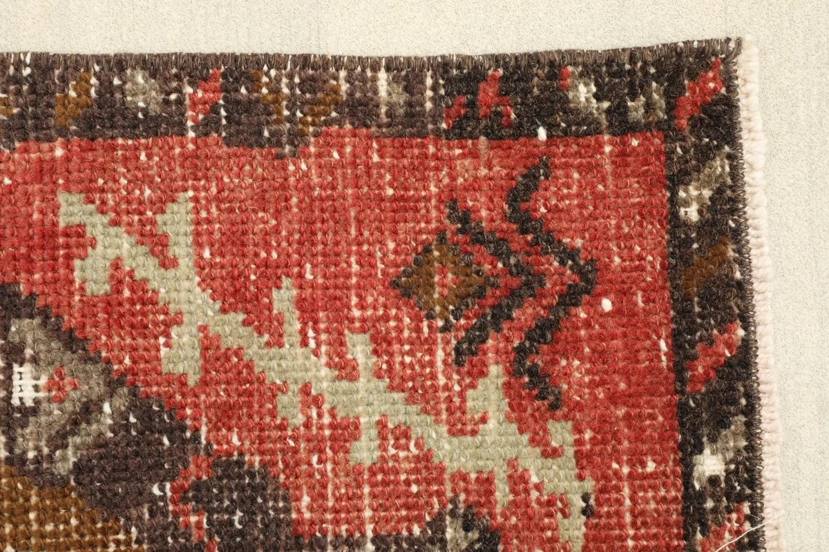 Edge detail of the rug's border and field, highlighting the low pile and vintage wear.