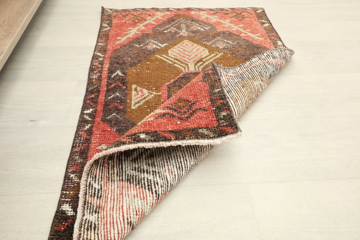 Angled view of the rug partially folded, displaying both the front design and the reverse side.