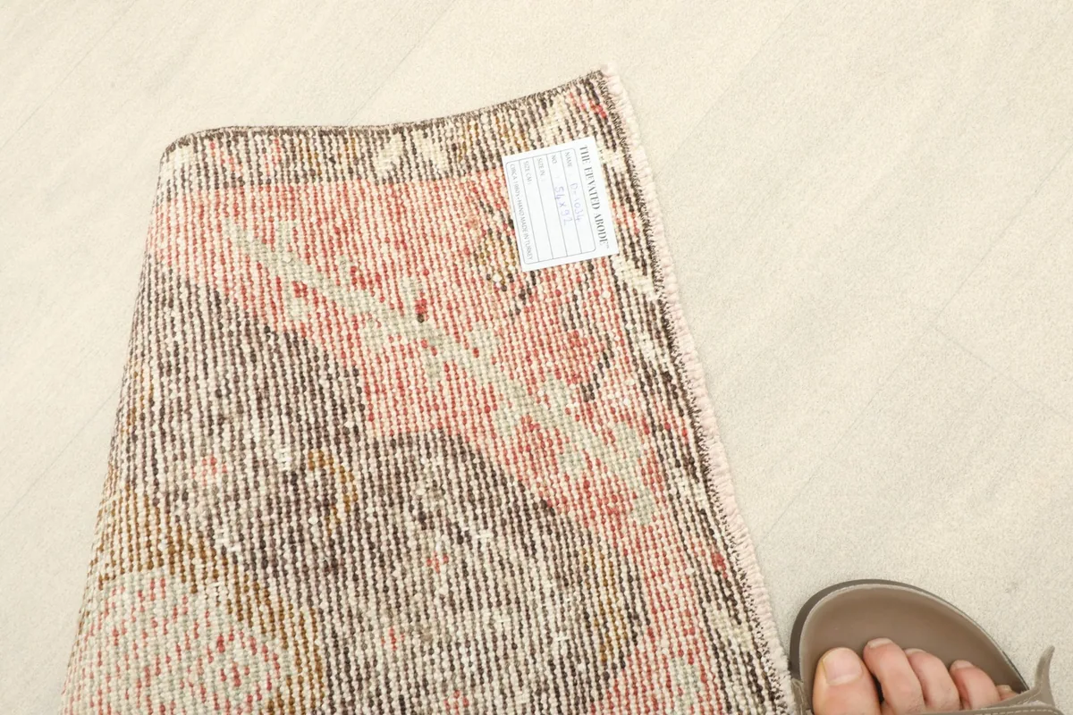 Close-up of the rug's back with a size label, next to a foot for scale.