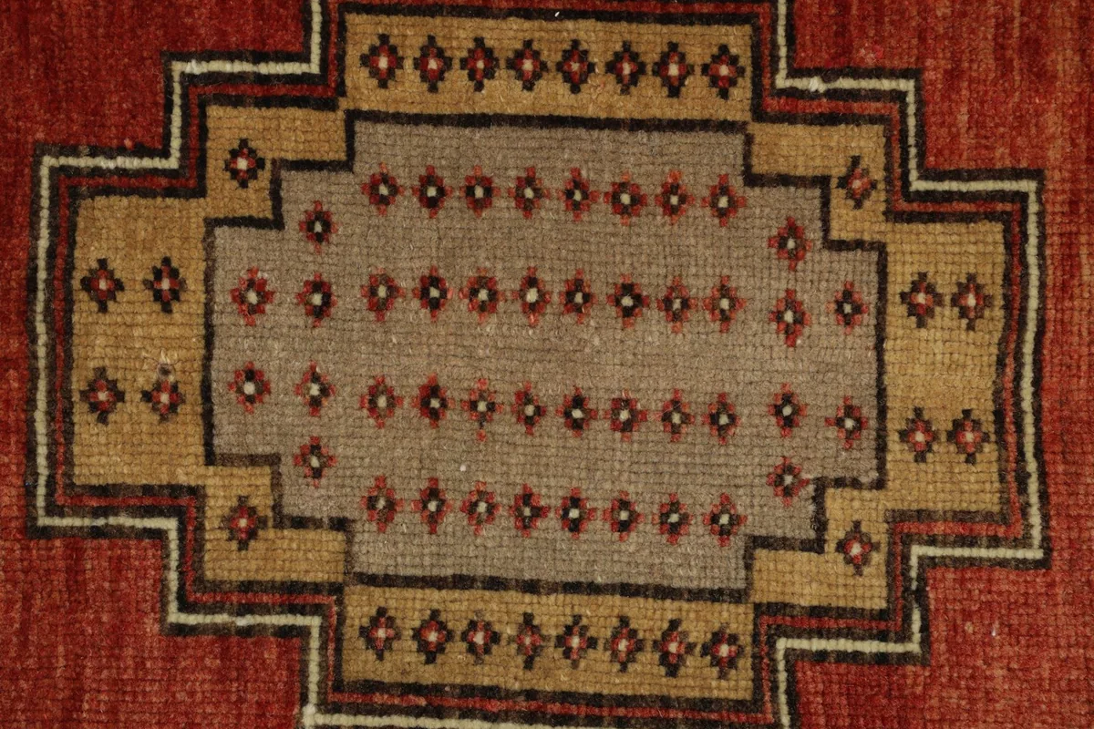 Close-up detail of a central beige and gray geometric medallion with small brown motifs.