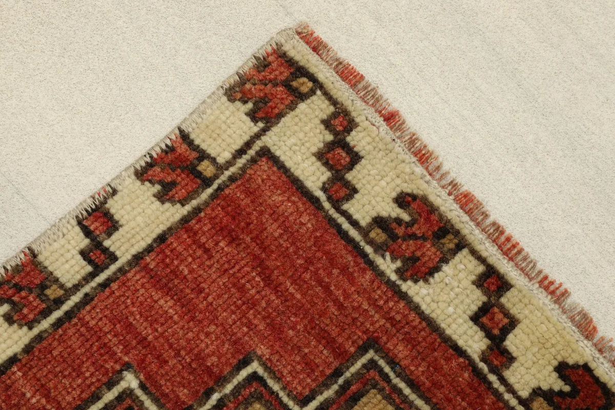 Close-up of the corner, showing the beige border with red and brown tribal elements.