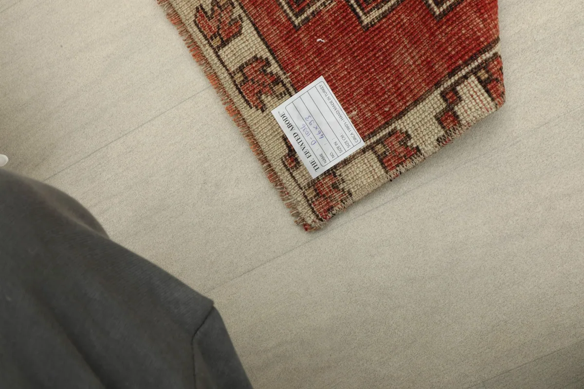 View of the rug's back side, revealing the hand-knotted cotton foundation and a product label.