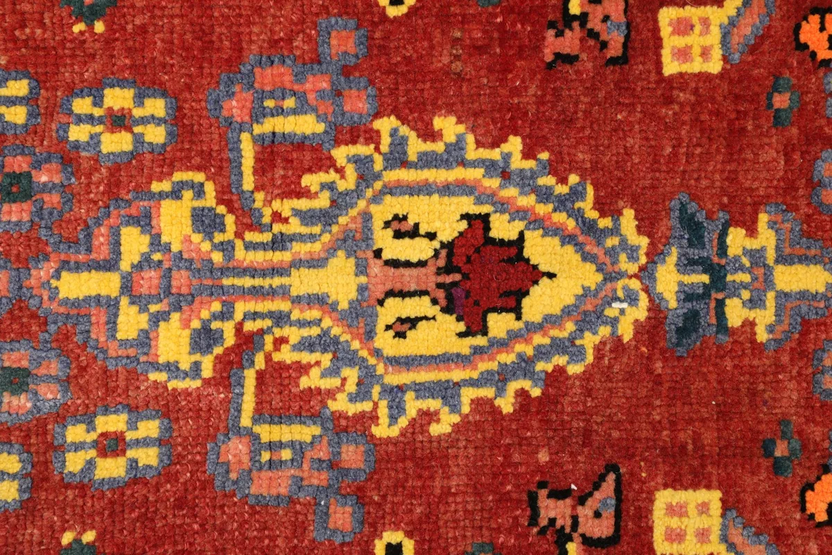 Close-up detail of the central yellow and navy medallion motif on the red field.