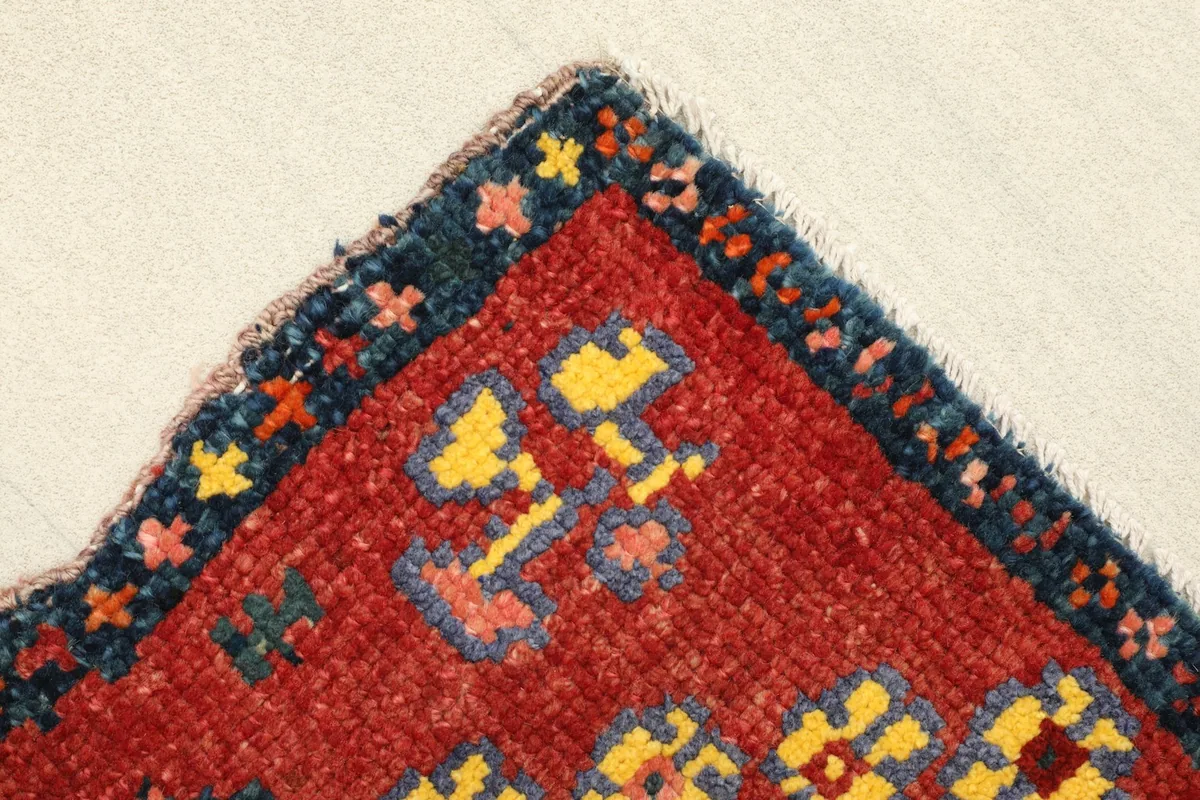 Corner detail of the rug, showing the navy border with small colorful geometric elements.