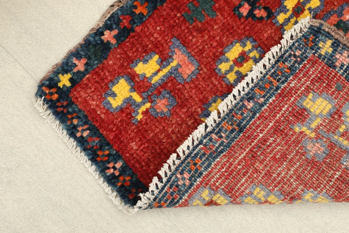 View of the rug's corner folded back, revealing the hand-knotted cotton foundation.