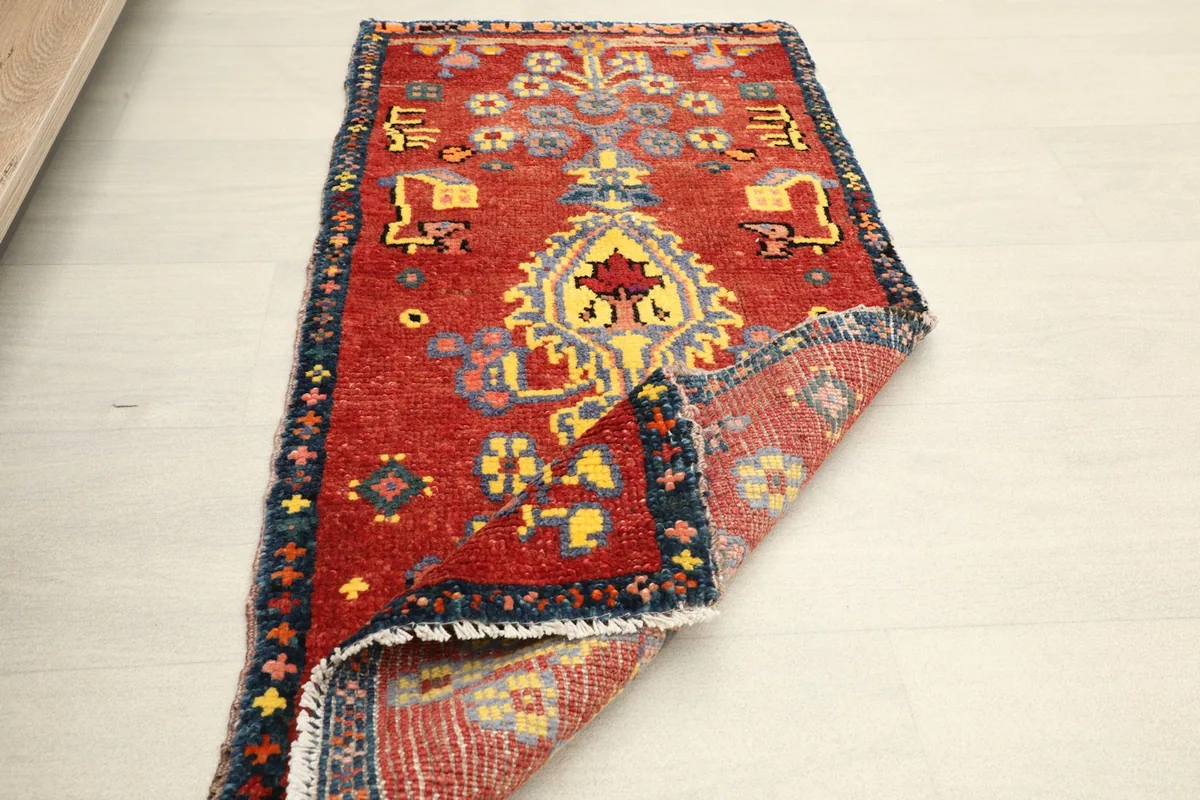 The red doormat partially folded, showing the flexibility and construction of the vintage piece.