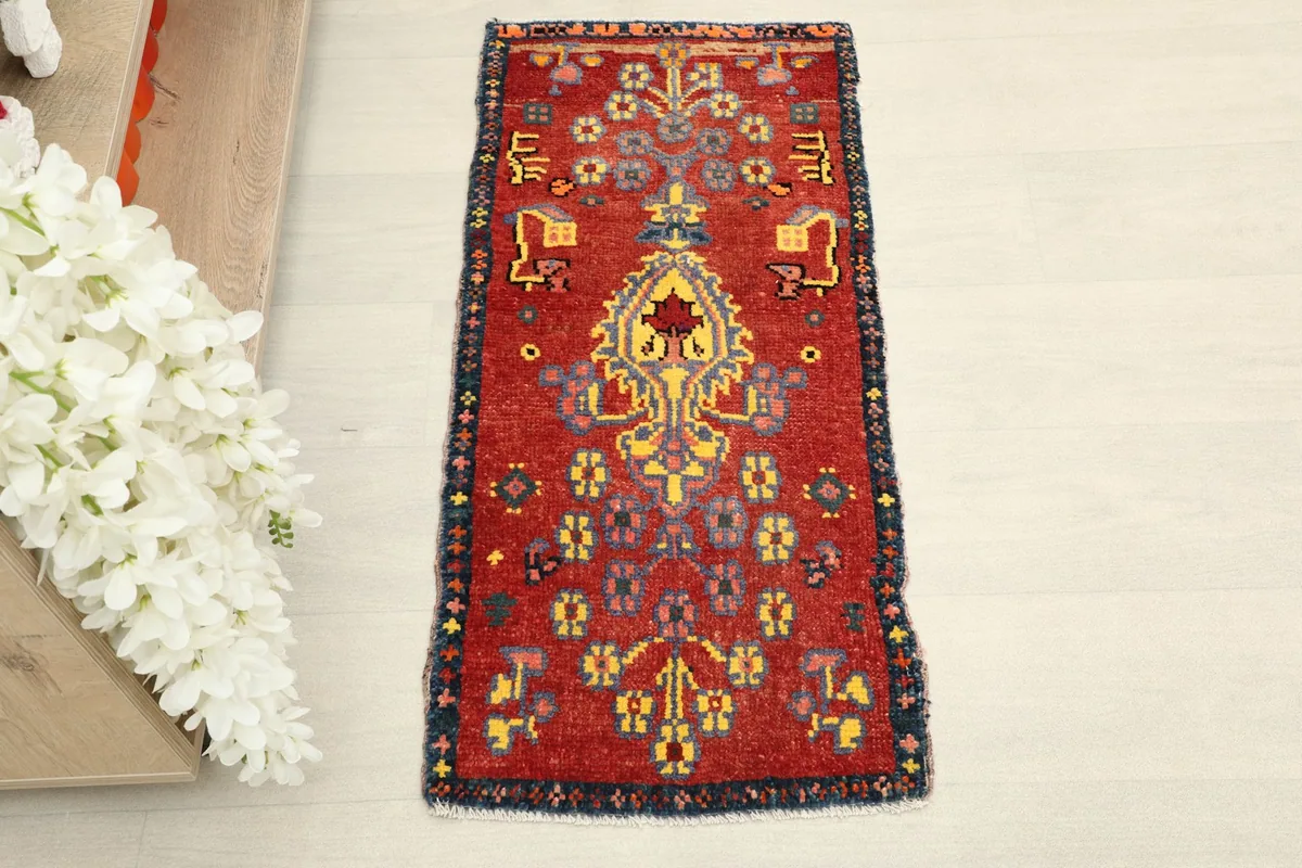 Overhead view of the red vintage doormat, showcasing its central medallion and tribal patterns.