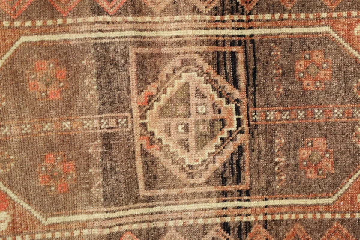 Close-up of the central geometric medallion and surrounding patterns in rust, brown, and beige