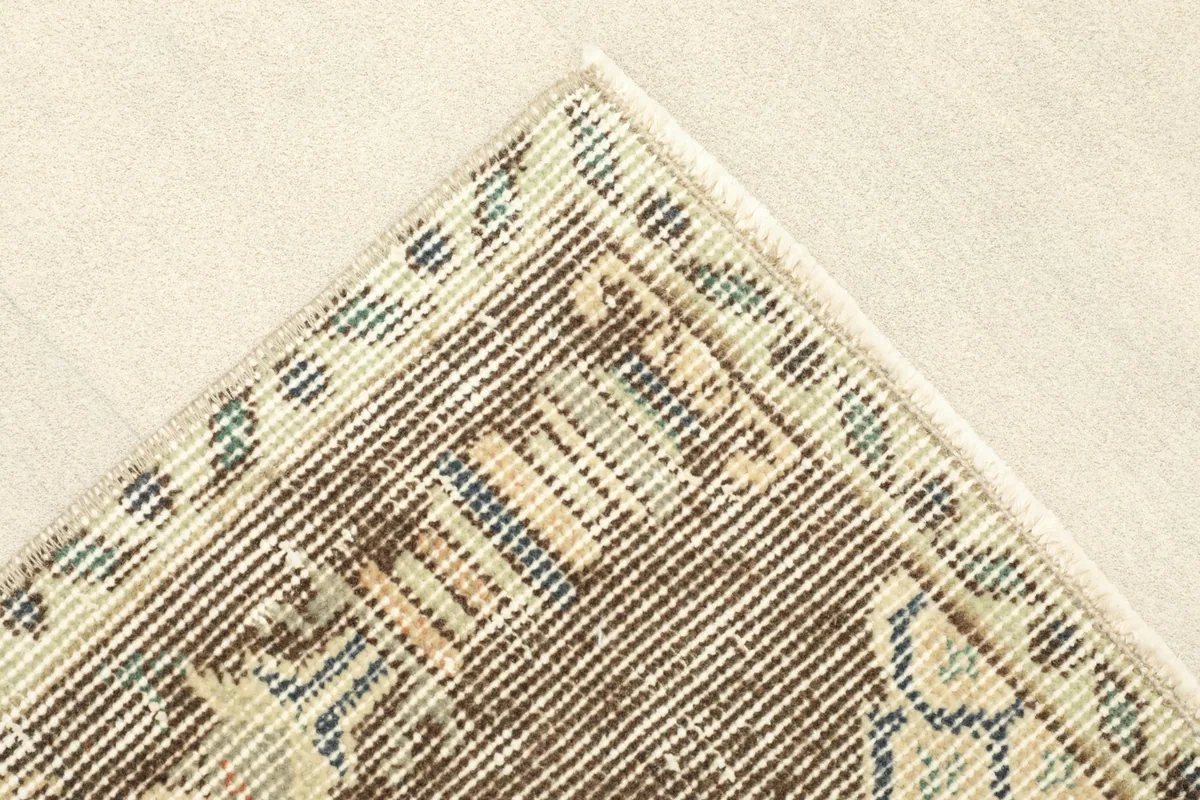 Detail of the corner and border design of the vintage rug, showing the colors and texture.