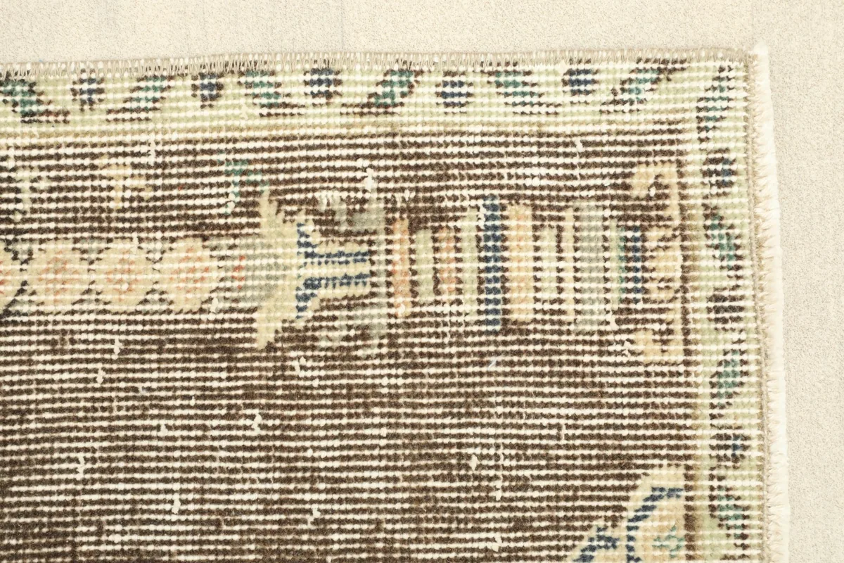 Close-up of the rug's border, displaying the intricate geometric patterns in beige and blue tones.