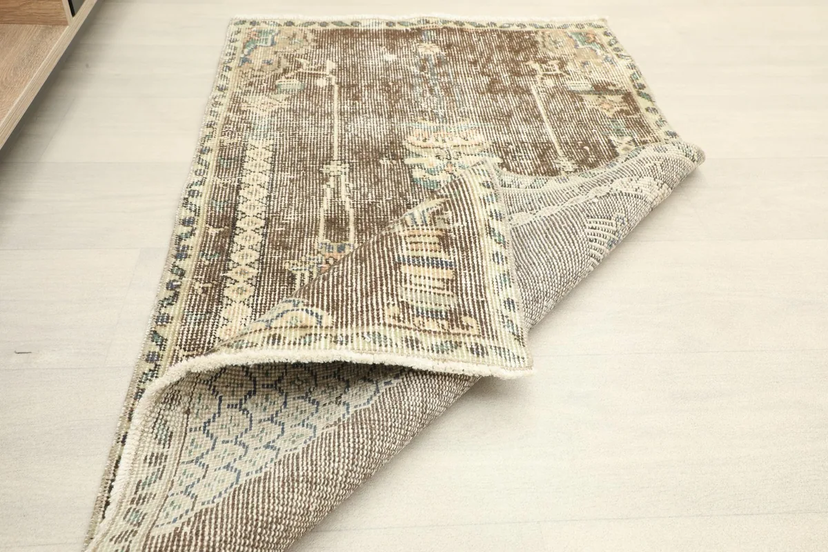 The rug partially folded, showing the flexibility and thickness of the vintage wool pile.