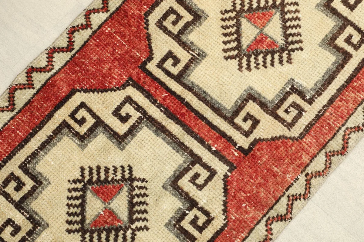 Angled view of the vintage Anatolian rug, highlighting the rust field and ivory geometric designs.