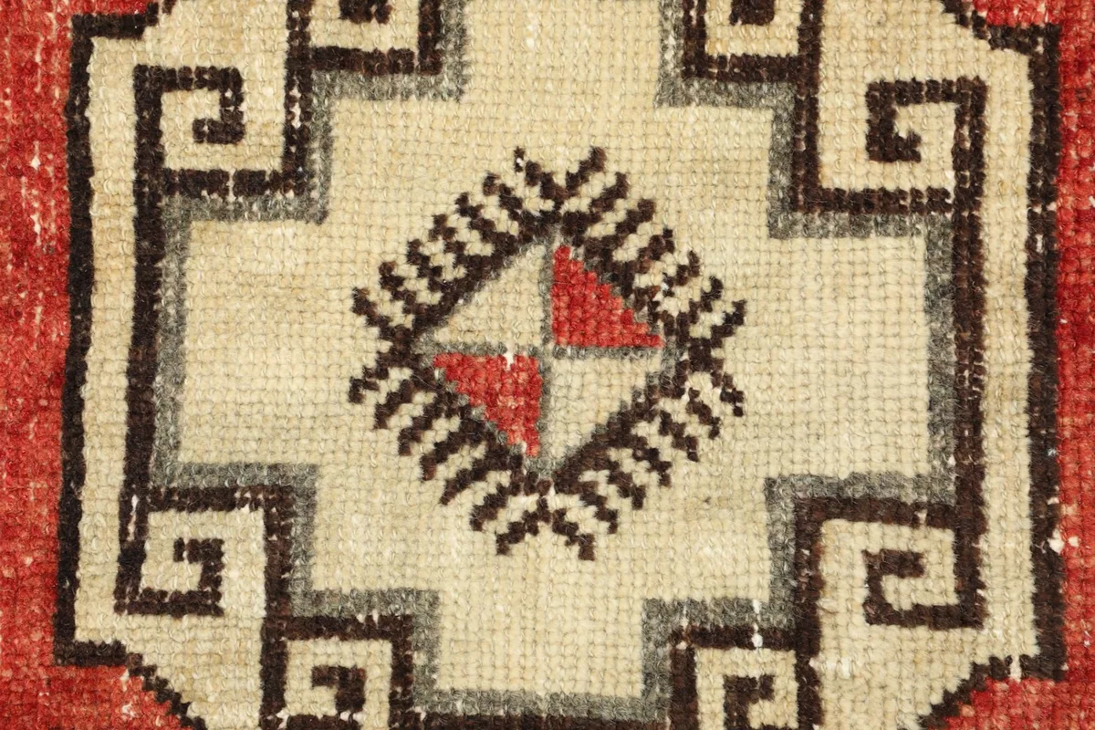 Close-up detail of a central ivory geometric motif with rust and black accents.