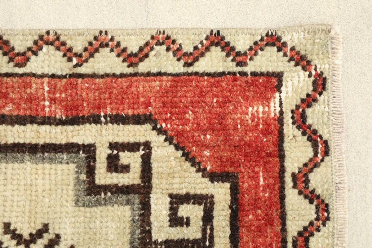Close-up of the rug's edge, revealing the texture of the rust field and ivory border.