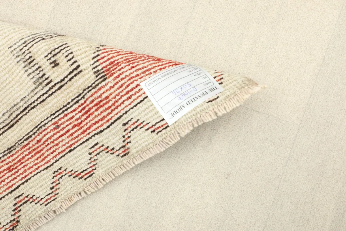 Detail of the rug's back with a label, showing the hand-knotted wool pile on cotton foundation.
